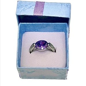 Silver colored ring with purple stone and 3 faux diamonds on each side.